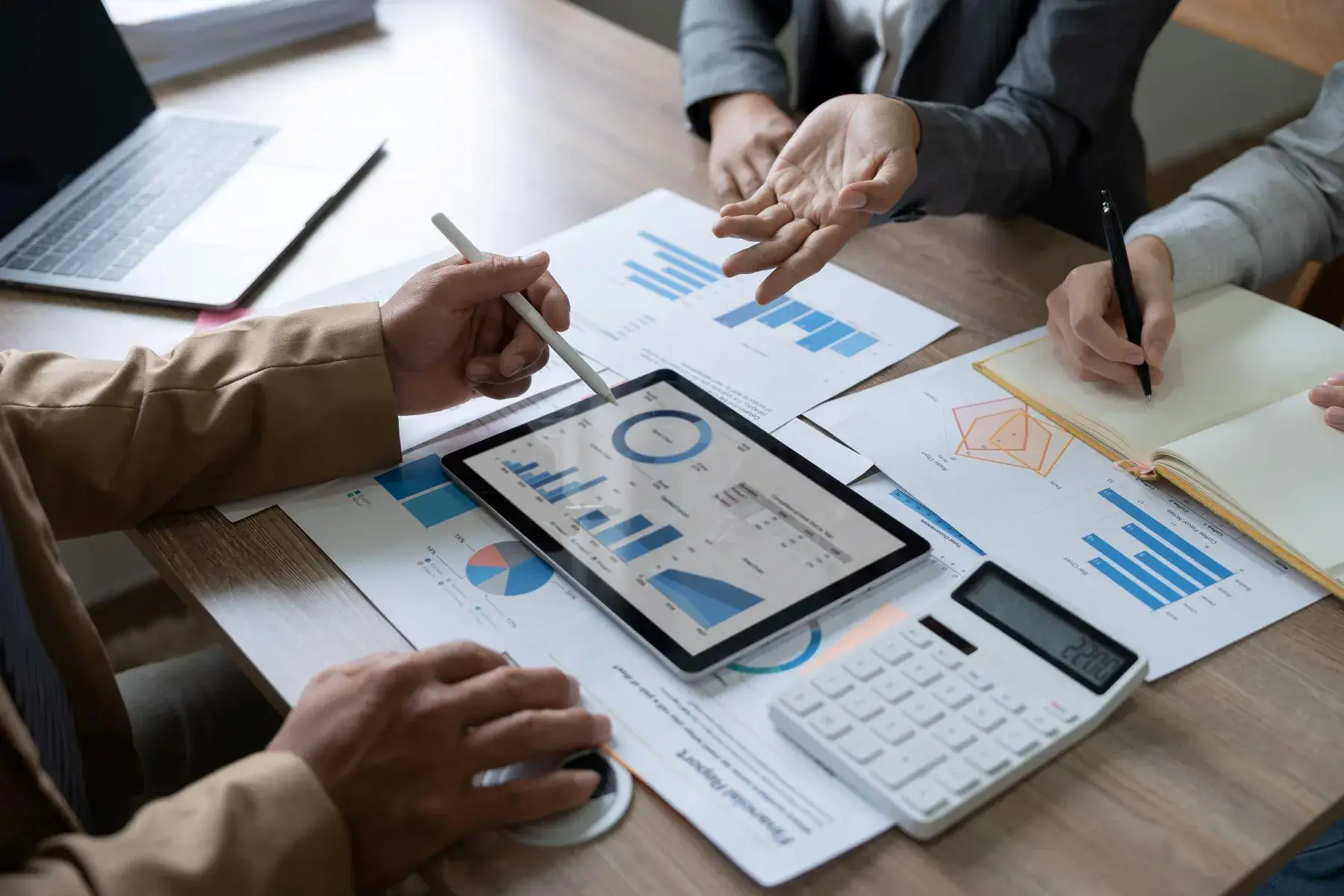 Team analyzing financial data on a tablet and discussing reports at a meeting